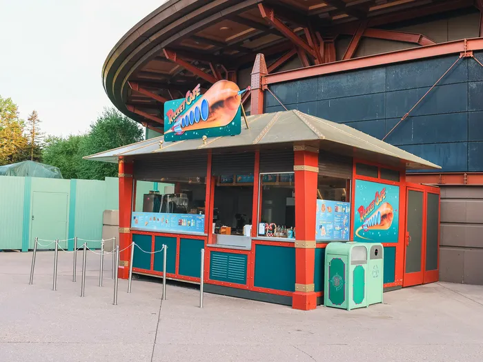 Kiosque rouge et turquoise du Rocket Café avec son enseigne, sur l’esplanade de Discoveryland.