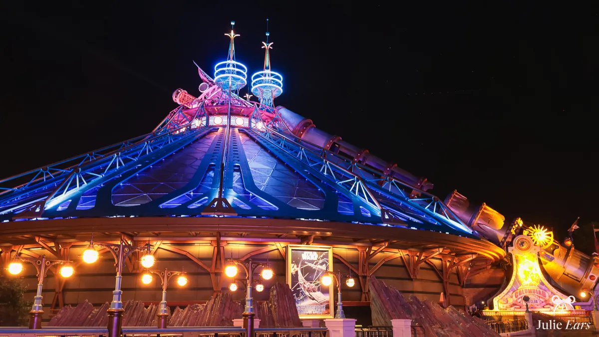 Star Wars Hyperspace Mountain dome lit in blue and purple at night in Discoveryland, with a Star Wars poster and the Columbiad cannon lit up