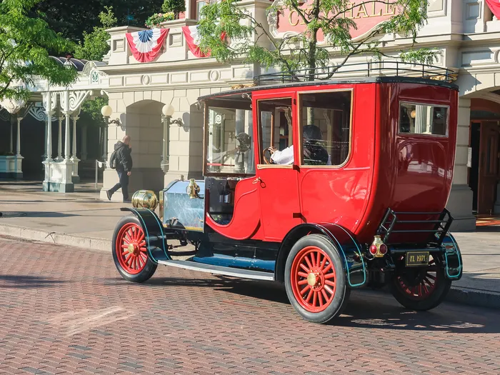 Voiture-limousine rouge d’époque à roues rouges circulant sur les pavés de Main Street