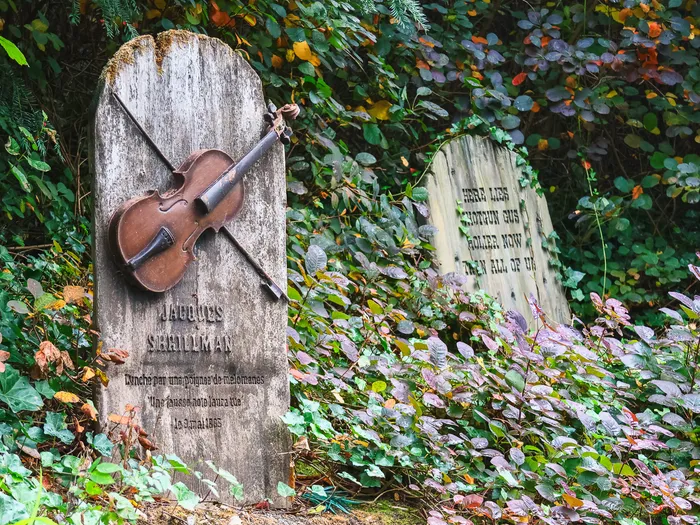 Pierre tombale gravée d’un violon dans le cimetière fleuri de Phantom Manor, attraction de Frontierland.