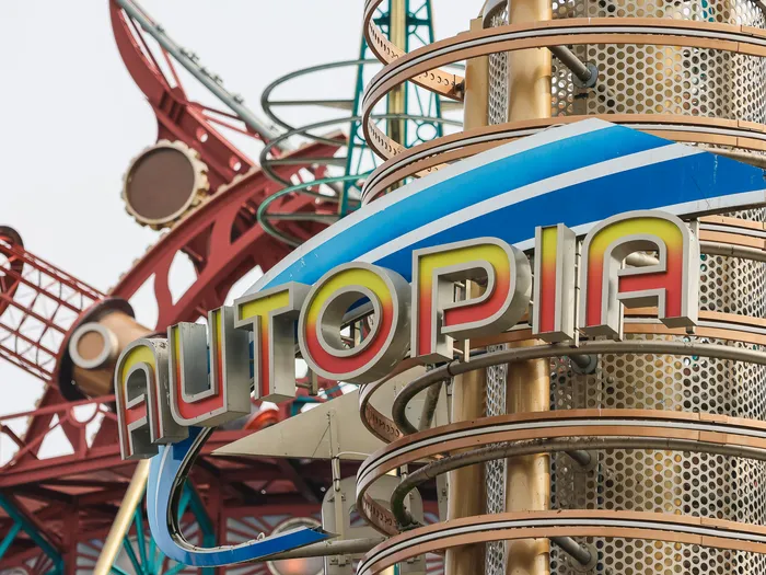 Enseigne stylisée « Autopia » bleu et jaune devant une structure métallique rouge de l’attraction, à Discoveryland.