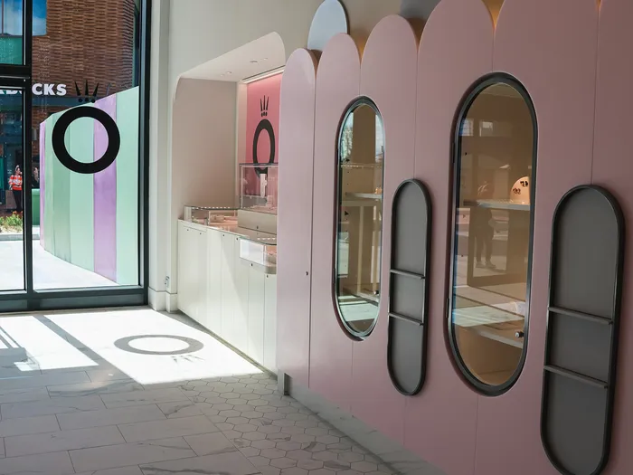 Inside Disney Glamour, a pink wall with oval alcoves and jewellery cases at Disney Village