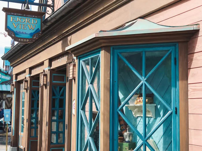 Corner of the Fjord View Shop frontage, with a blue scalloped roof and a turquoise lattice window