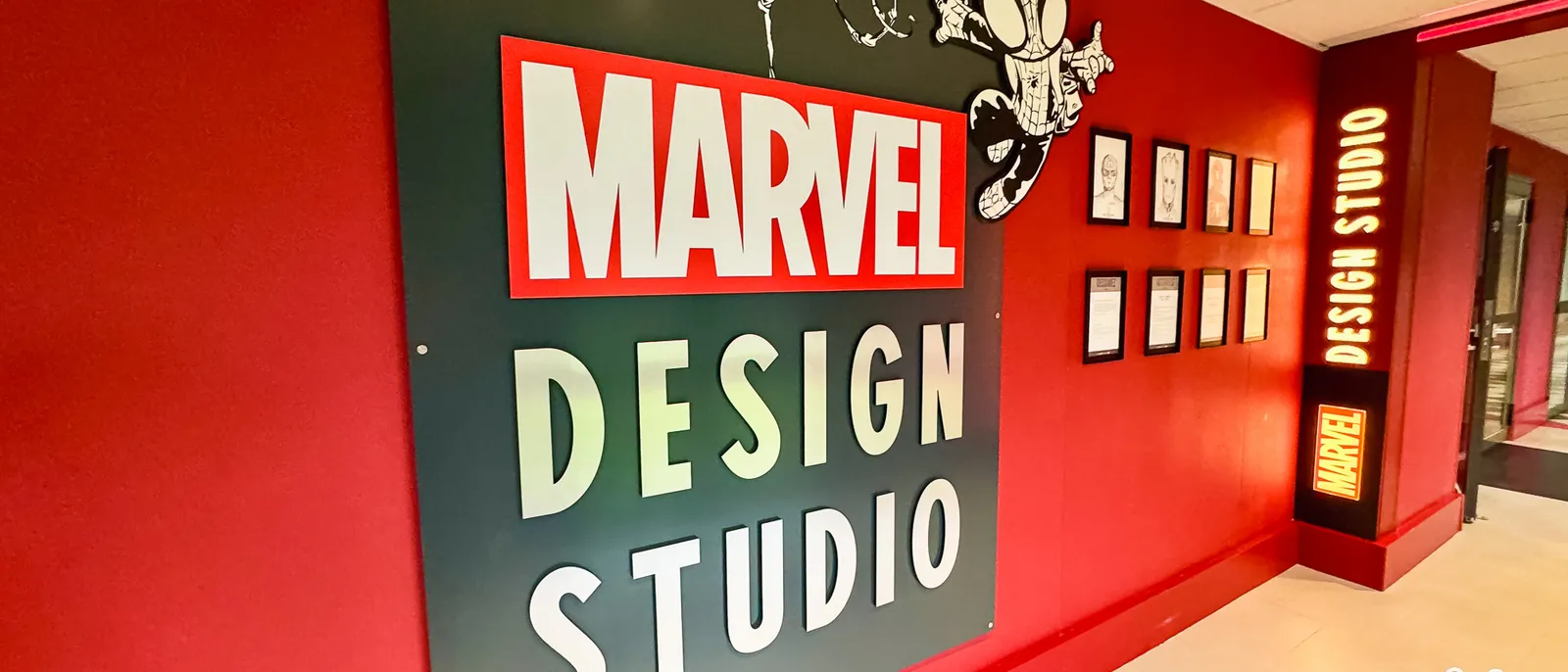 Le mur rouge du Marvel Design Studio à l’hôtel New York The Art of Marvel, avec logo Marvel et croquis encadrés.