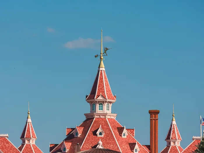 Toits roses à pignons et flèches du Disneyland Hotel sous un ciel bleu