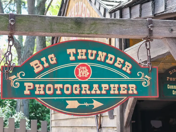 Enseigne verte à bordure rouge Big Thunder Photographer suspendue à des chaînes, Frontierland, Disneyland Paris