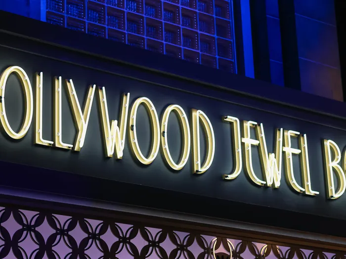 White neon "Hollywood Jewel Box" sign lit up on the dark front of the shop, at Disneyland Paris.