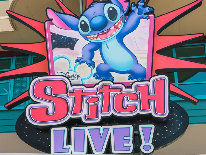 Enseigne colorée de Stitch Live! avec le personnage Stitch qui salue, sur la façade du spectacle
