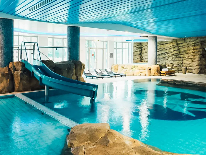 Piscine intérieure du Dream Castle Hotel avec toboggan bleu, rochers et étoile au fond du bassin.