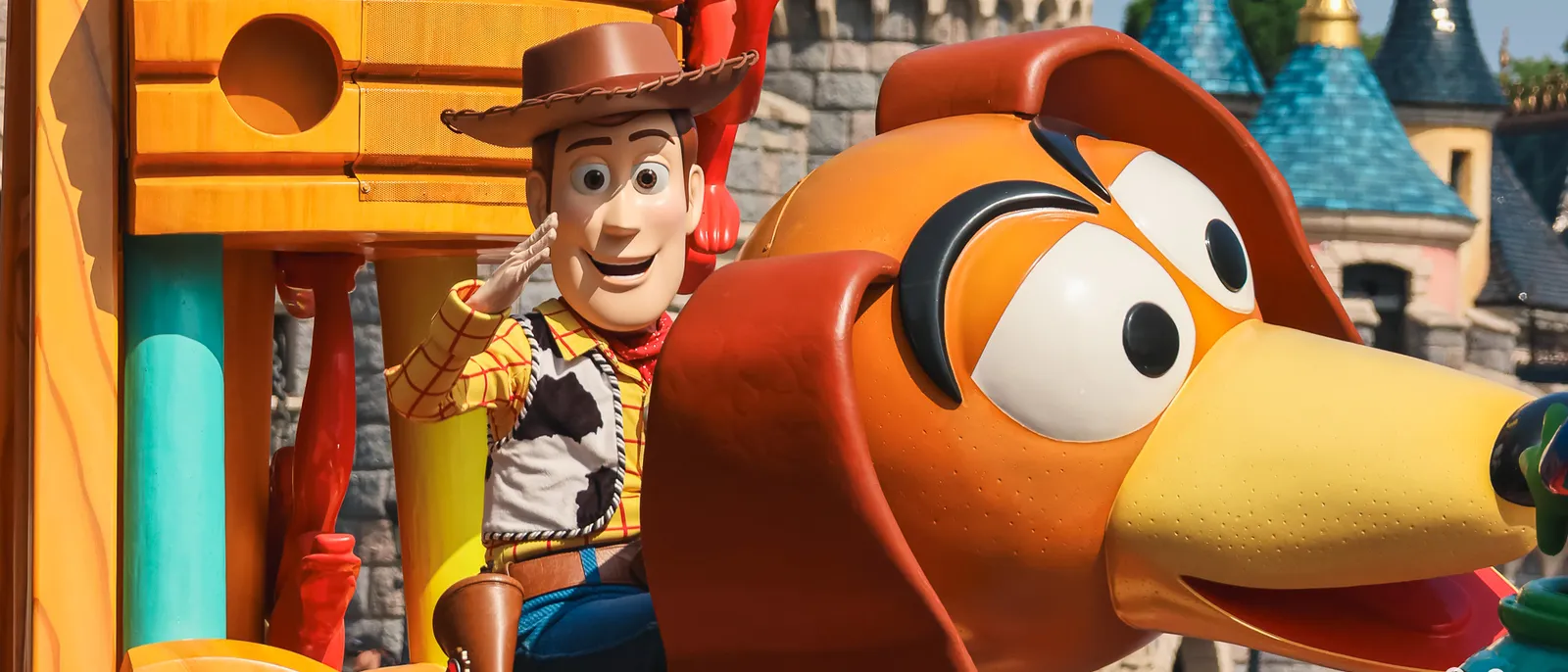 Woody fait le salut militaire sur un char de parade près du chien Zigzag, château en fond, Disneyland Paris