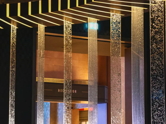 Colonnes de lumière dorée scintillantes encadrant l’accès à la réception, décor du Skyline Bar.