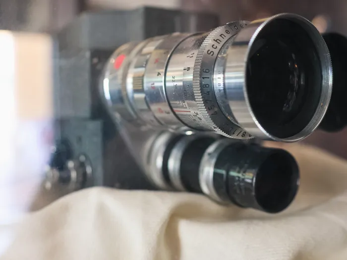 Close-up of a vintage film camera with a chrome Schneider lens, on display at Studio Photo
