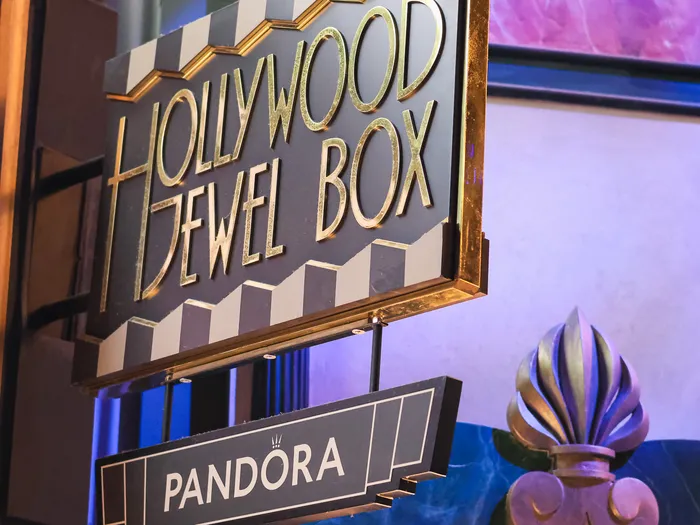 Black and white striped Art Deco sign with gold "Hollywood Jewel Box" lettering, hanging above a "Pandora" sign, at Disneyland Paris.