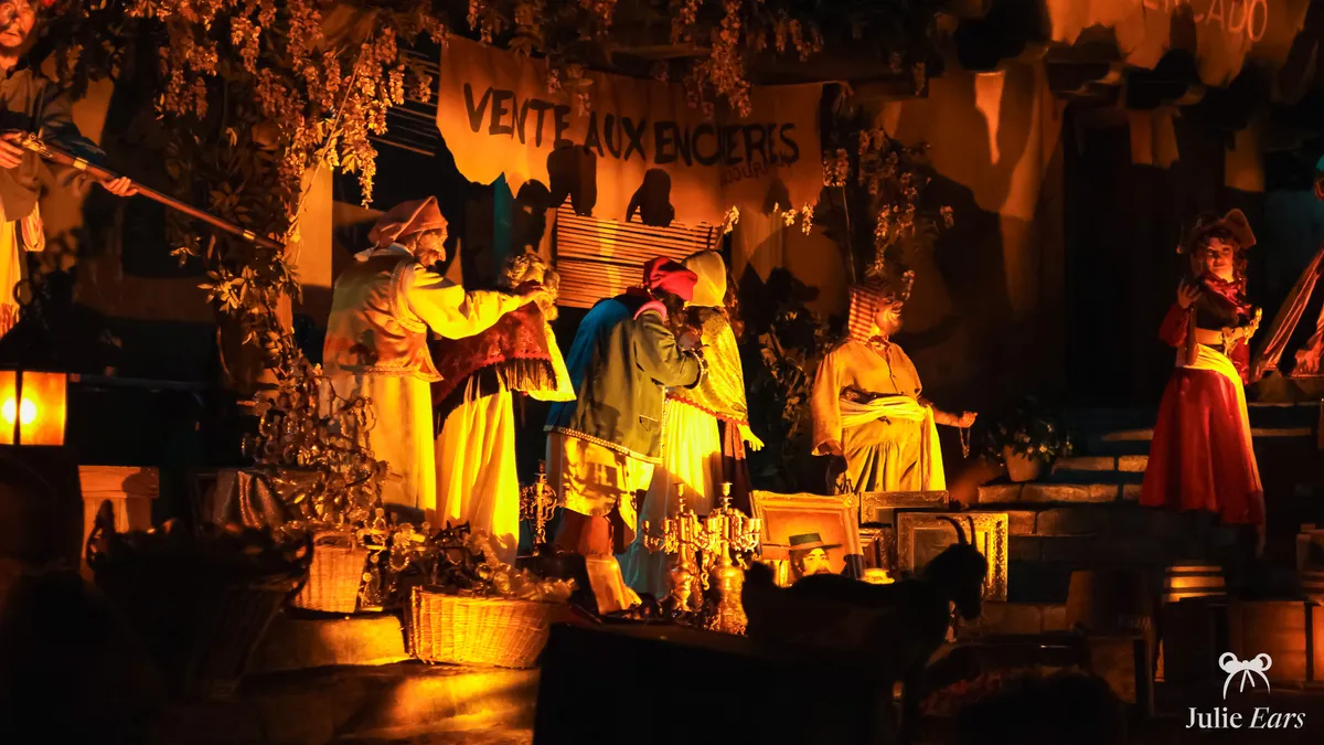 Auction scene in Pirates of the Caribbean at Disneyland Park: an "Auction" banner, village women lined up and a pirate holding a rifle