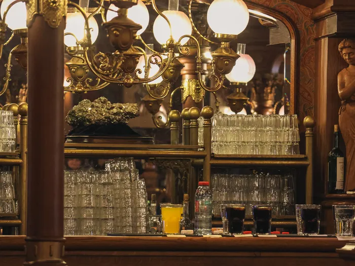 Comptoir en bois du Lucky Nugget Saloon garni de verres alignés sous des lustres en laiton, restaurant de Frontierland.