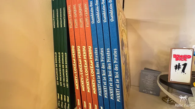 Disney comic books lined up on a shelf in a shop at Disneyland Paris, including Mickey and the Pirate King and Donald’s Holidays.