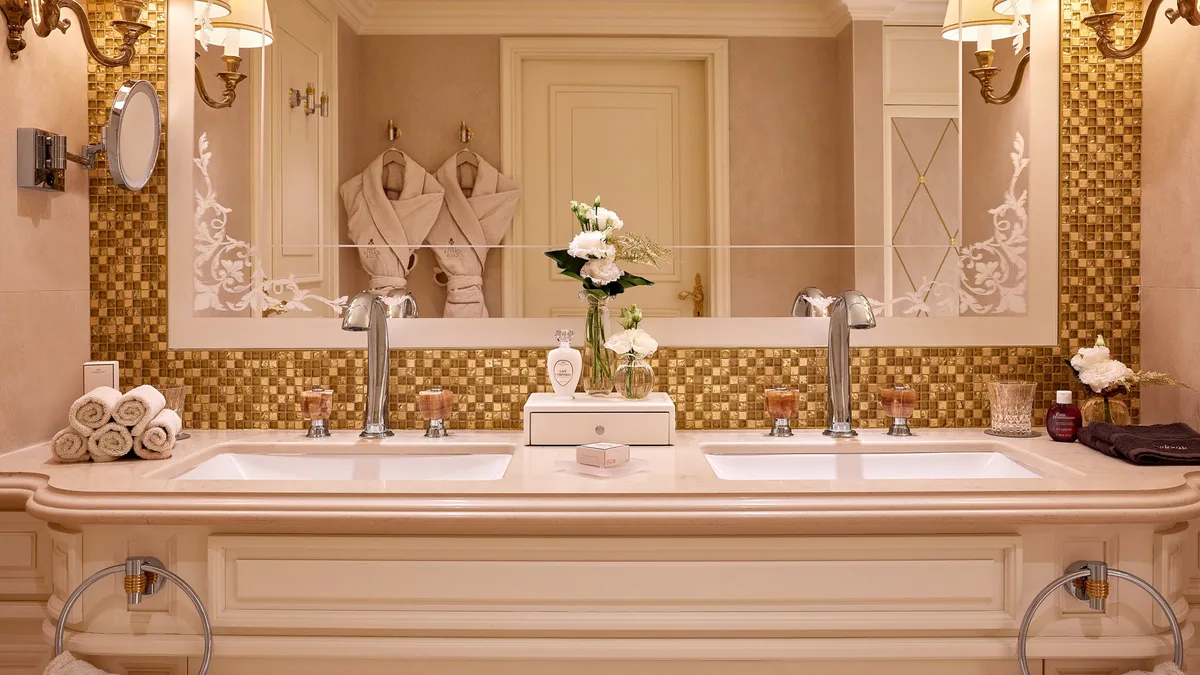 Salle de bain d'une chambre Club du Disneyland Hotel, double vasque, mosaïque dorée et peignoirs