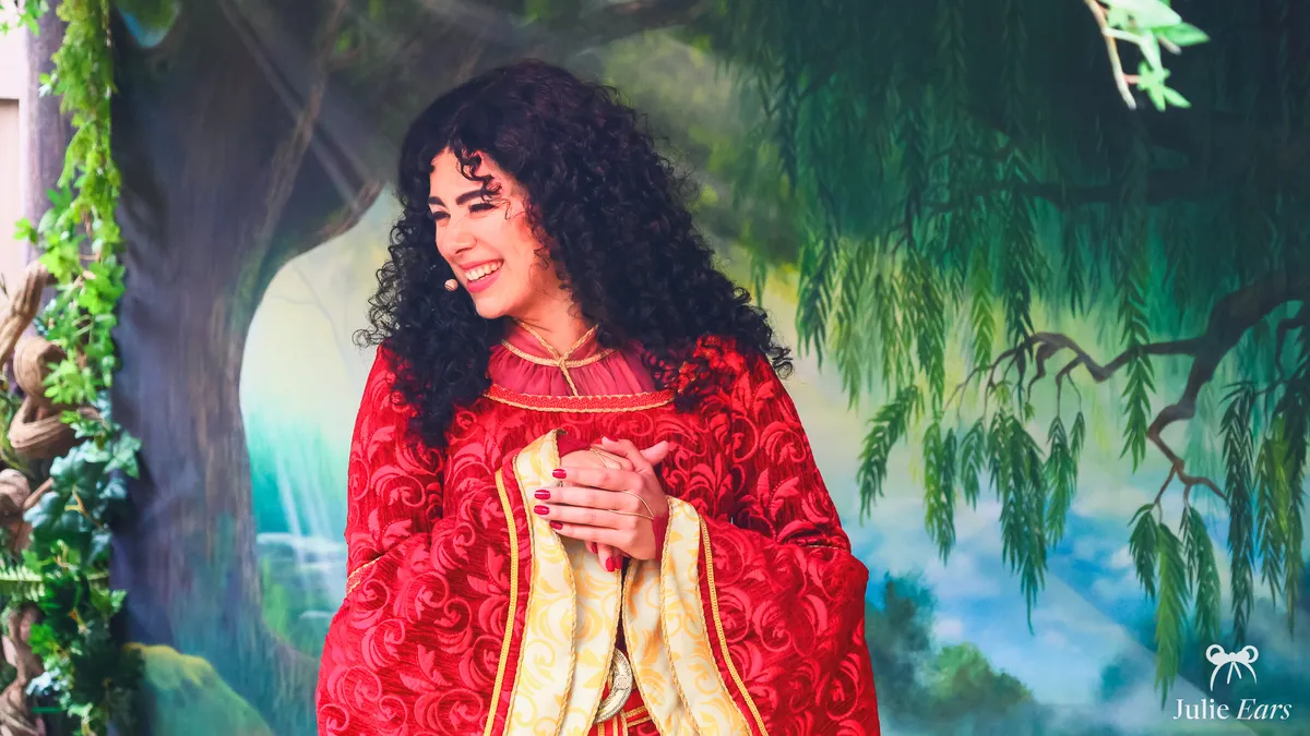Mother Gothel, with her long curly brown hair and red dress, during a show at Disneyland Paris.