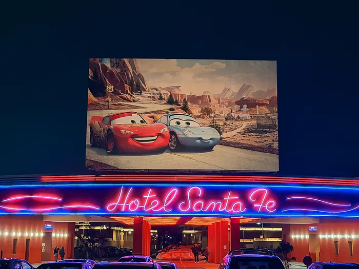 Entrée du Disney Hotel Santa Fe la nuit, enseigne néon et panneau Cars avec Flash McQueen, à Disneyland Paris.