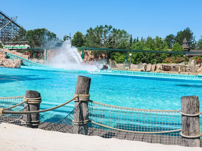 Grand bassin bleu et gerbe d’eau d’une attraction aquatique, coaster en bois au loin à Europa-Park.