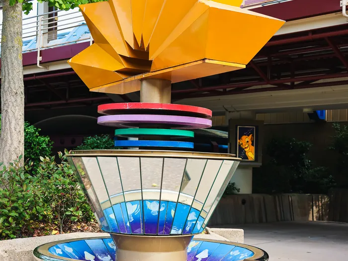 Sculpture-fontaine aux pétales dorés et vasque à miroirs bleus, devant le théâtre de Mickey PhilharMagique à Discoveryland.
