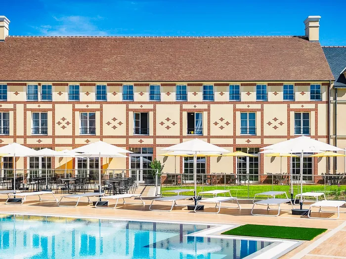 Piscine extérieure avec transats et parasols devant l’aparthotel Staycity près de Disneyland Paris