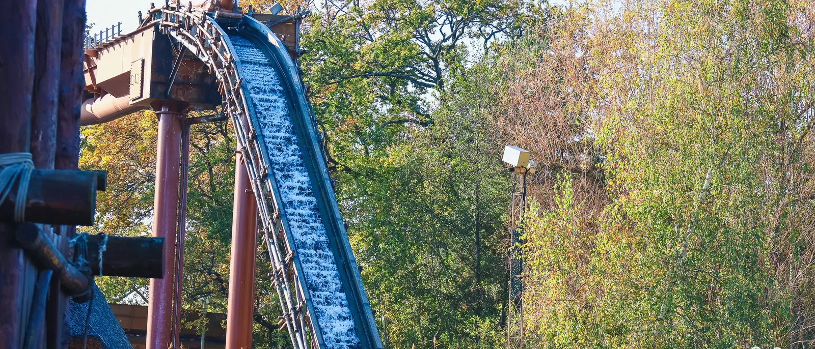Grande descente du Menhir Express, rampe d’eau bleue et charpente en bois, barque au sommet du plan incliné, arbres d’automne