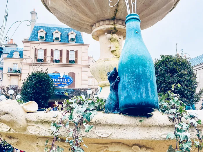 Fontaine décorée d’un rat et d’une bouteille bleue devant la façade de l’attraction Ratatouille