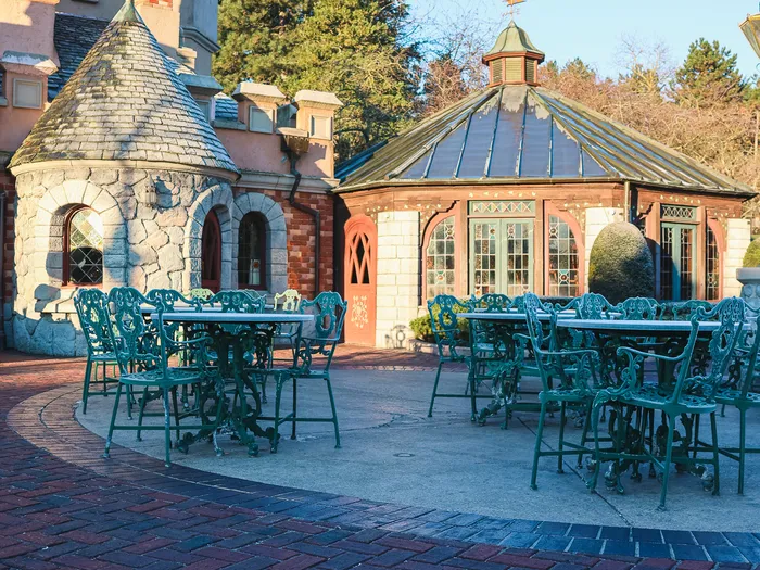 Terrasse de Toad Hall Restaurant, tables et chaises en fer vert devant un pavillon vitré