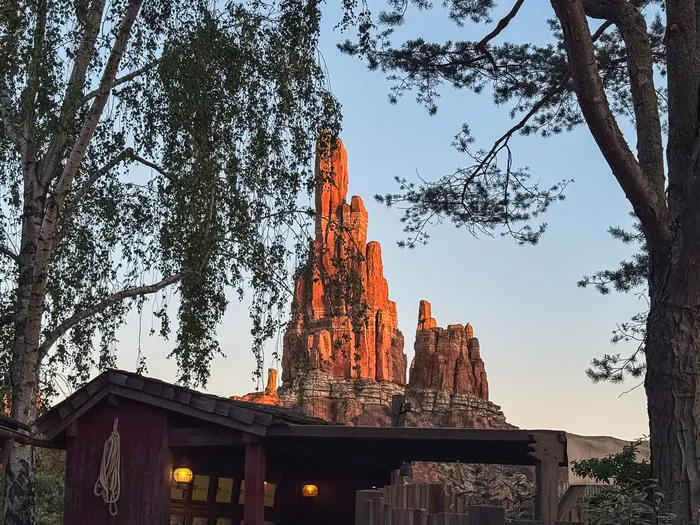 Pitons rocheux rouges de Big Thunder Mountain éclairés au soleil couchant, vus entre les arbres