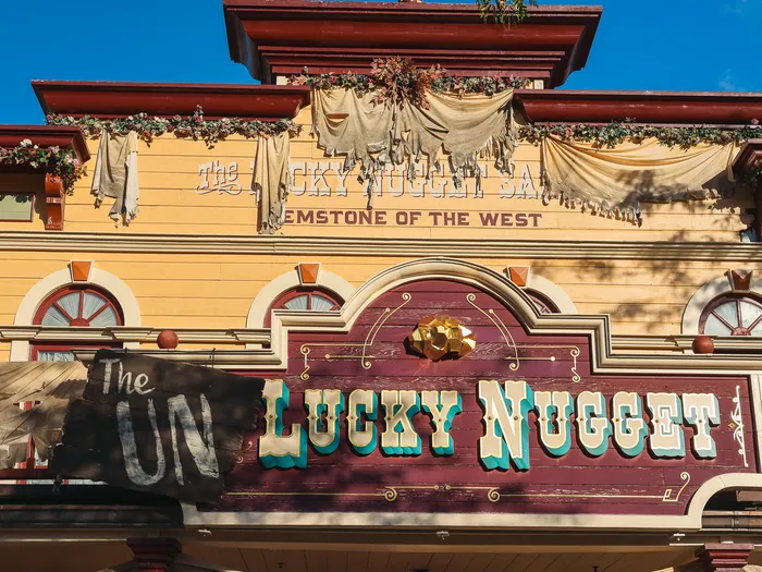 Façade jaune et bordeaux du Lucky Nugget Saloon habillée pour Halloween en « The Unlucky Nugget », à Frontierland.