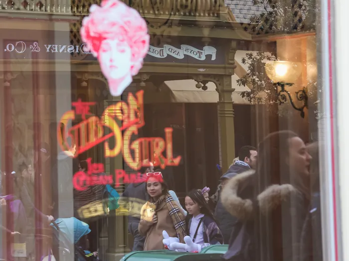 Vitrine dorée du Gibson Girl Ice Cream Parlour avec l’illustration rose de la Gibson Girl, reflets de visiteurs.