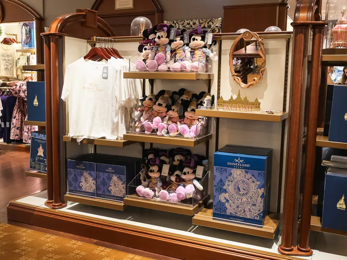 Étagères présentant des peluches Mickey et Minnie en tenue royale et des coffrets Disneyland Hotel.