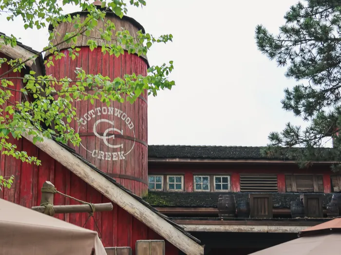 Grange rouge et silo Cottonwood Creek du restaurant Cowboy Cookout Barbecue à Frontierland, entourés de verdure.