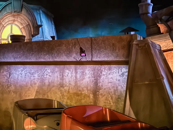 Véhicule en forme de rat au pied d’un mur géant dans une scène intérieure de l’attraction Ratatouille