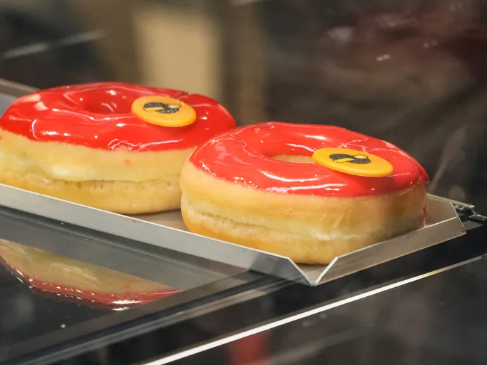 Deux donuts à glaçage rouge vif ornés d’une pastille, en vitrine au kiosque Searchlight.