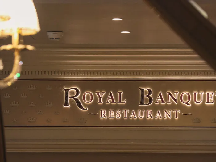 Enseigne dorée Royal Banquet Restaurant sur mur orné de couronnes, sous un lustre à pampilles au Disneyland Hotel.