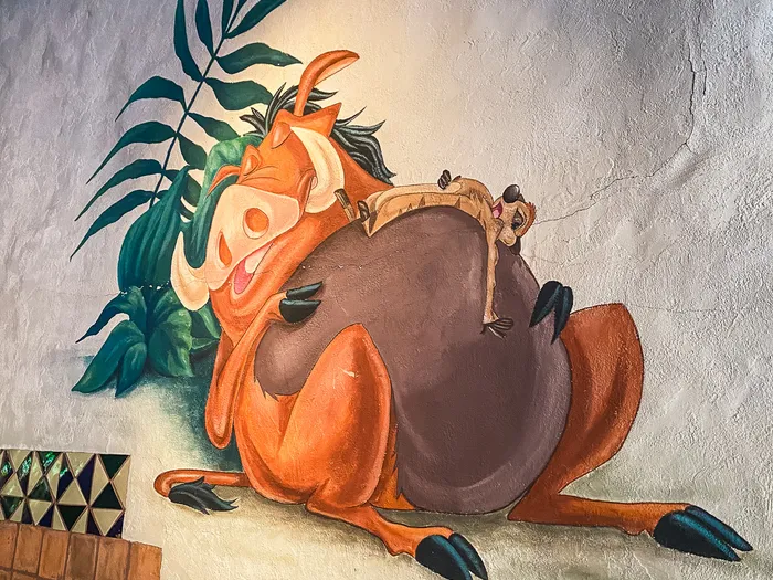 Peinture murale de Timon endormi sur le dos de Pumbaa dans la salle du restaurant Hakuna Matata