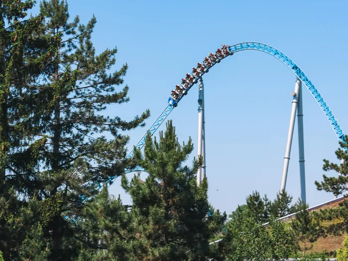 Train du coaster Blue Fire franchissant une grande courbe bleue au-dessus des pins à Europa-Park.