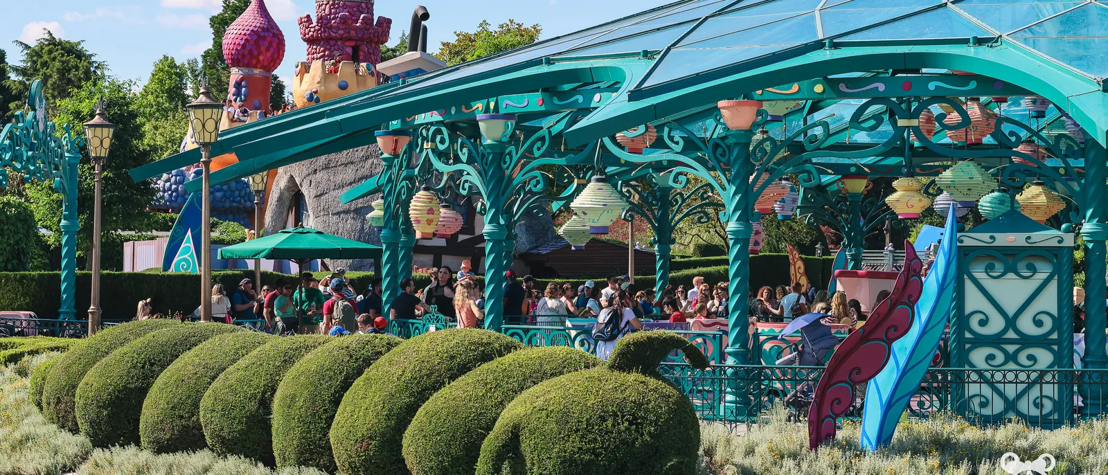 Attraction des tasses Mad Hatter’s Tea Cups à Fantasyland, haies taillées en chenille au premier plan, Disneyland Paris.