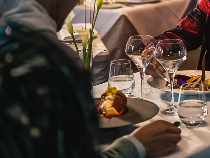 Couple dînant au Manhattan Restaurant dans une ambiance tamisée, verres de vin et assiette dressée