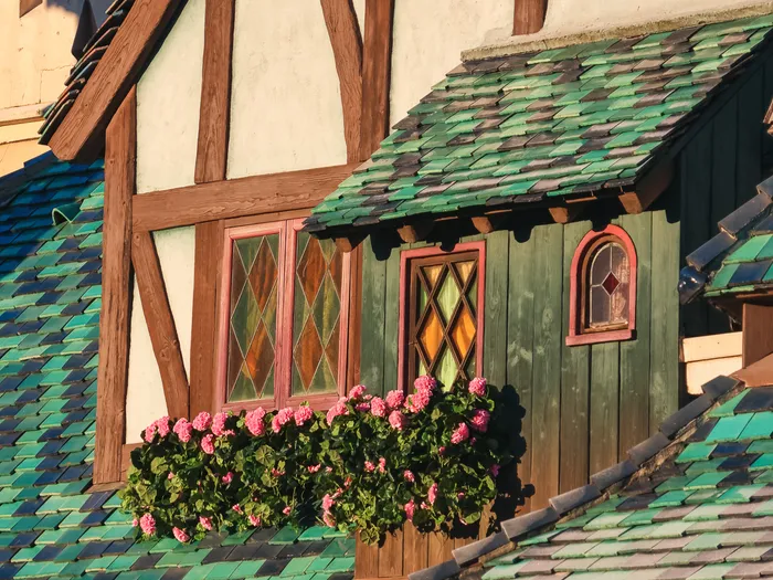 Façade à colombages et toits en tuiles vertes de Peter Pan’s Flight, avec une jardinière de fleurs roses à Fantasyland.
