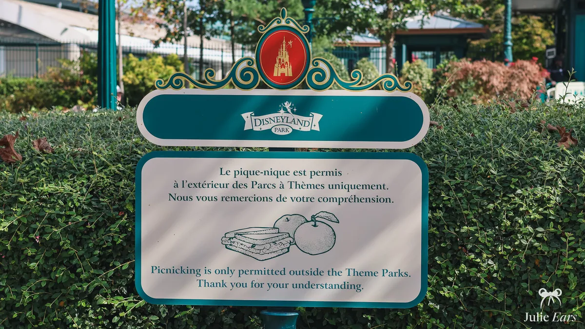 Disneyland Park sign saying that picnics are only allowed outside the theme parks, in French and English