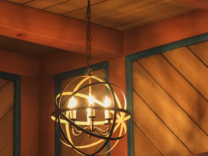 Lustre sphérique en métal suspendu sous un plafond en bois dans la salle du restaurant Nordic Crowns Tavern