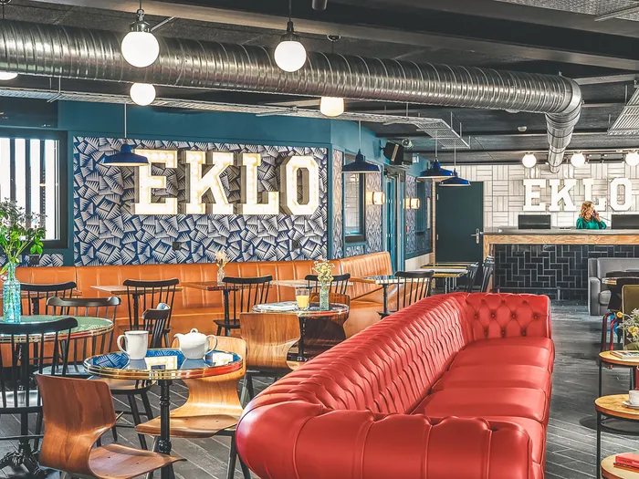 Industrial-style bar area at the Eklo, with a red buttoned banquette and white EKLO letters on the wall.