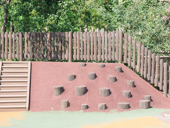 Butte souple parsemée de rondins pour grimper et escalier de bois à l’aire de jeux du Frontierland Playground