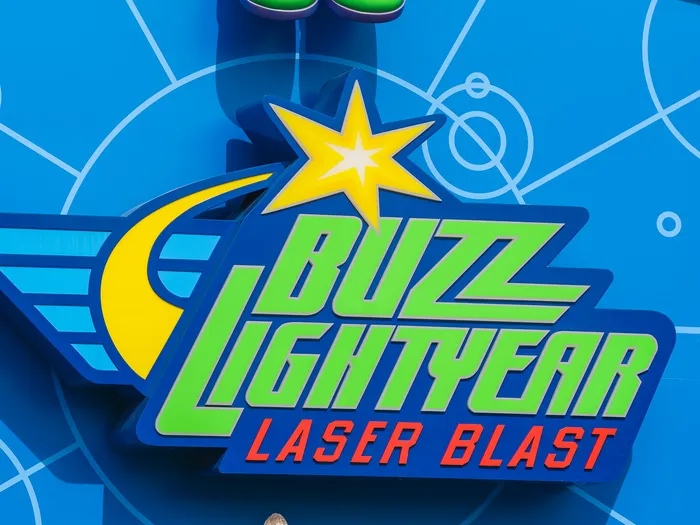 Enseigne colorée Buzz Lightyear Laser Blast sur un mur bleu à constellations, à Discoveryland.