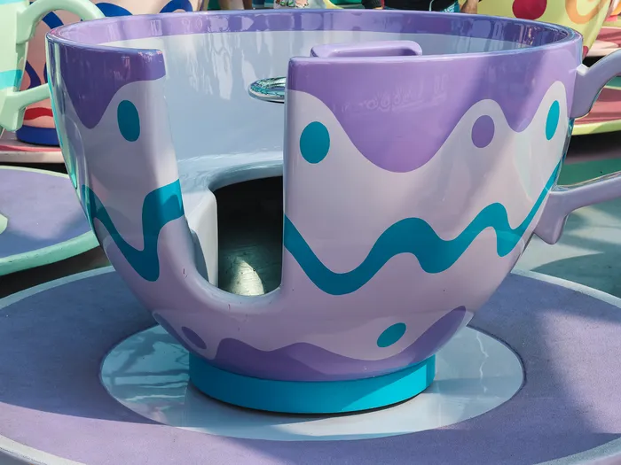 Tasse tournante violette à vagues bleues sur sa soucoupe, l’une des tasses du manège Mad Hatter’s Tea Cups à Fantasyland.