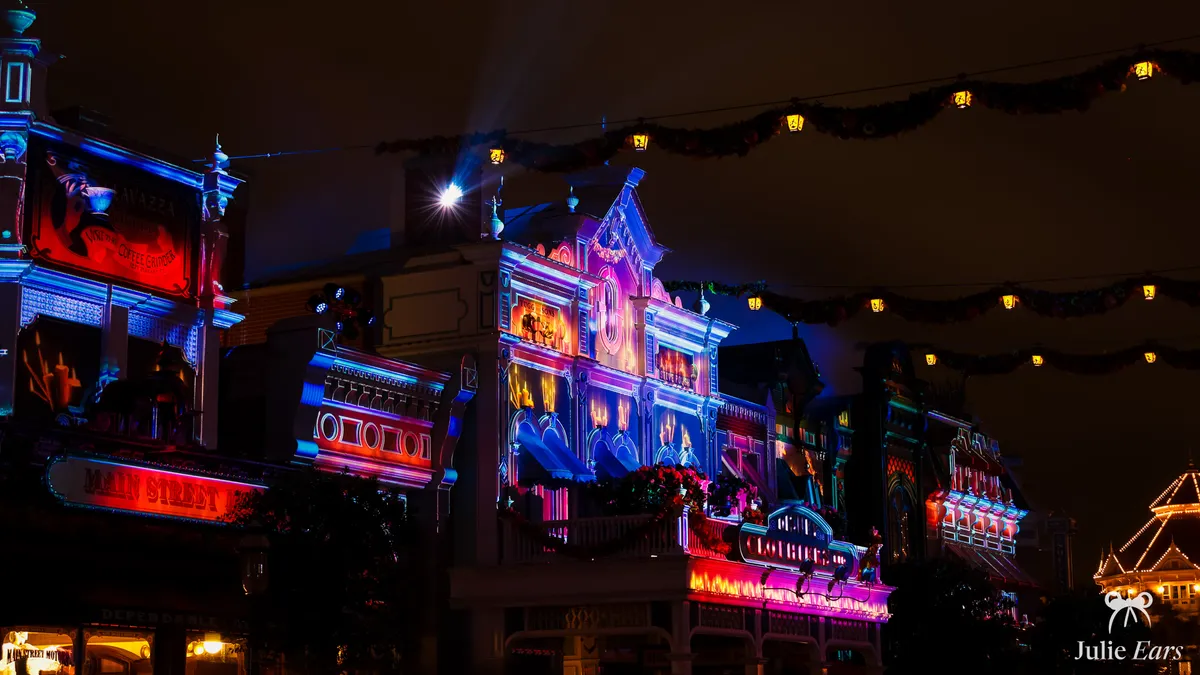 Façades victoriennes de Main Street U.S.A. éclairées de violet et de rouge la nuit d’Halloween.