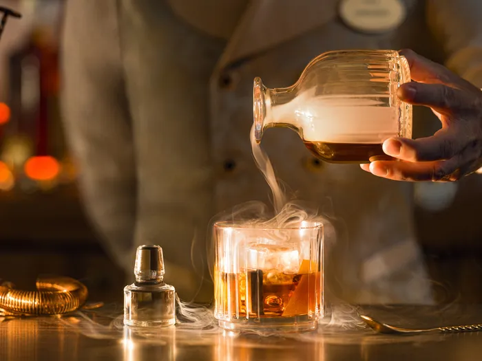 Cocktail ambré fumé versé au comptoir du Fleur de Lys Bar, au Disneyland Hotel